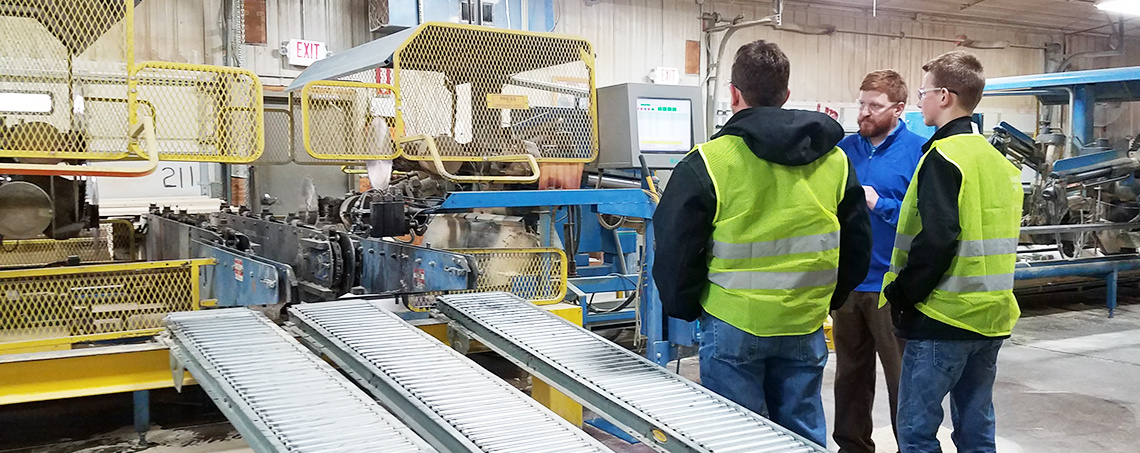 A plant manager talking with two guys on a plant tour